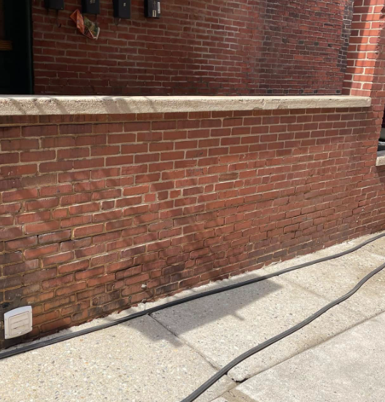 Brick wall covered in dark grime before washing